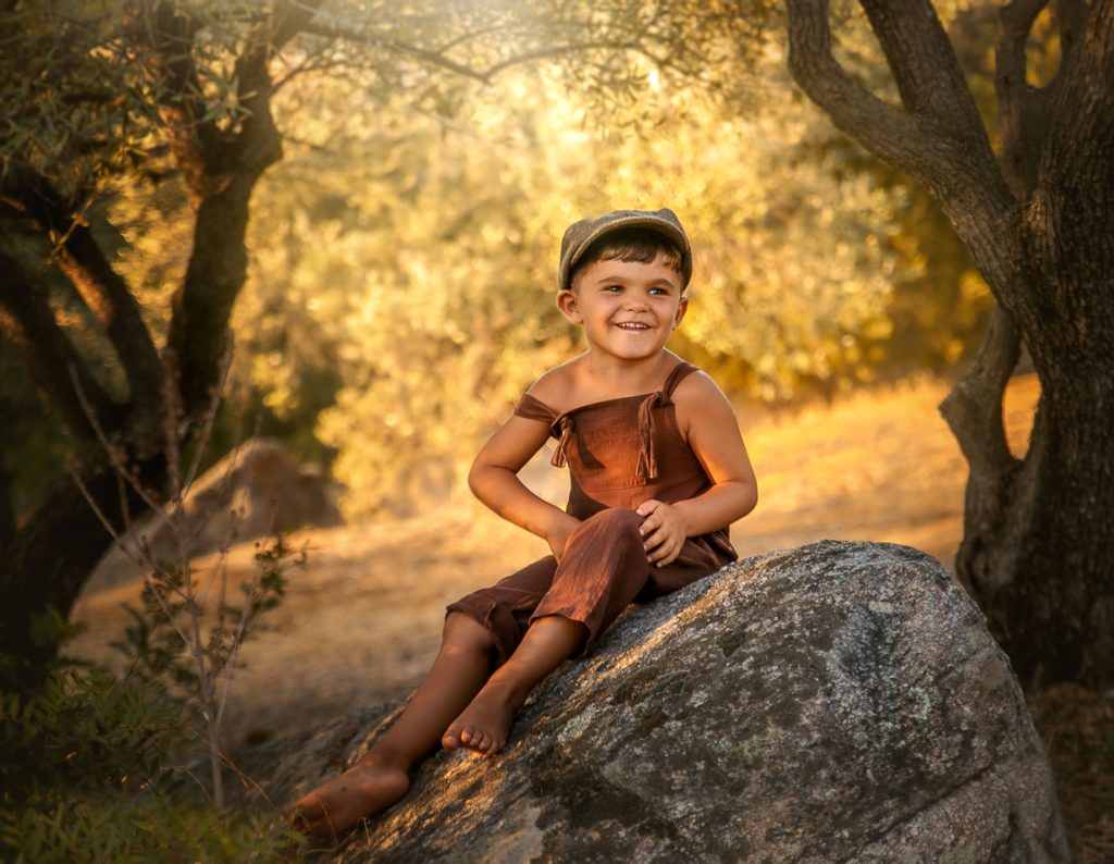 Retrato de niño sonriente en entorno exterior durante sesión infantil